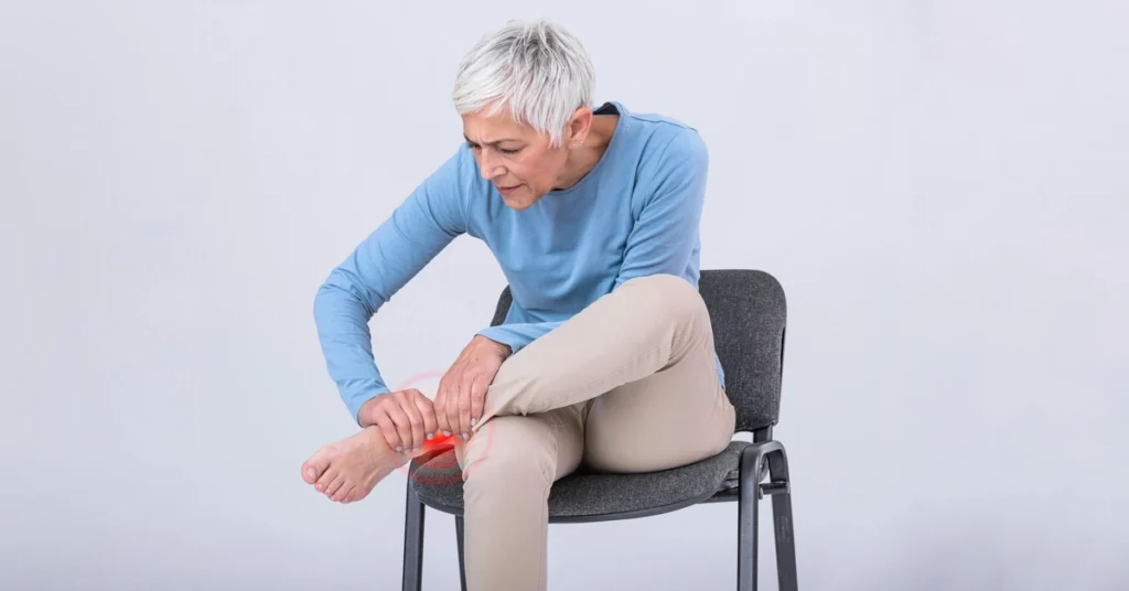 Kobieta w podeszłym wieku trzyma się za bolącą kostkę