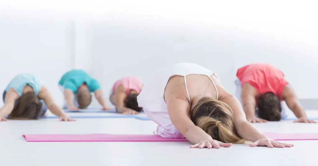 Grupa osób wykonuje skłon do przodu na leżąco