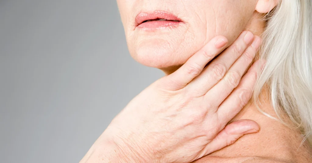 Dojrzała kobieta dotyka swojej szyi