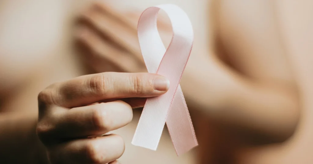 Naga kobieta trzyma różową wstążkę będącą symbolem walki z rakiem piersi